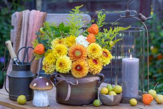 dahlias in a pot on a deck with fall decor