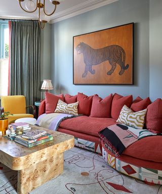 colorful living room with yellow accent chair, dark pink sofa, pale blue walls and tiger artwork