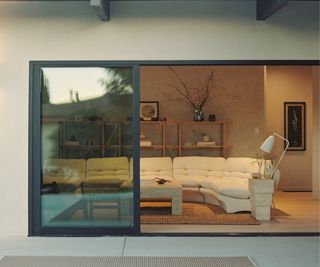 White sofa, black framed glass sliding doors, wooden shelves