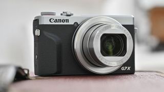 En tændt Canon PowerShot G7 X Mark III placeret på en lædersofa
