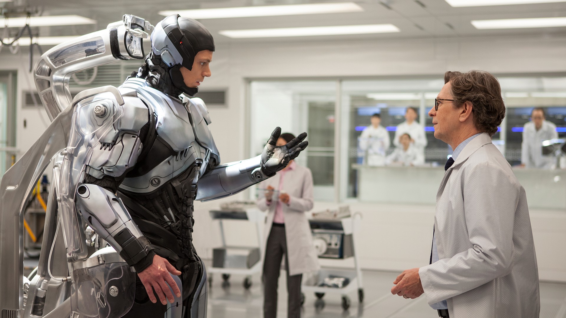 Still uit de film RoboCop (2014).  Hier zien we RoboCop tegenover een wetenschapper in een lab staan,