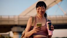 Woman looking at phone after workout holding water bottle