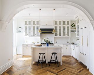 white kitchen with island and wooden flooring