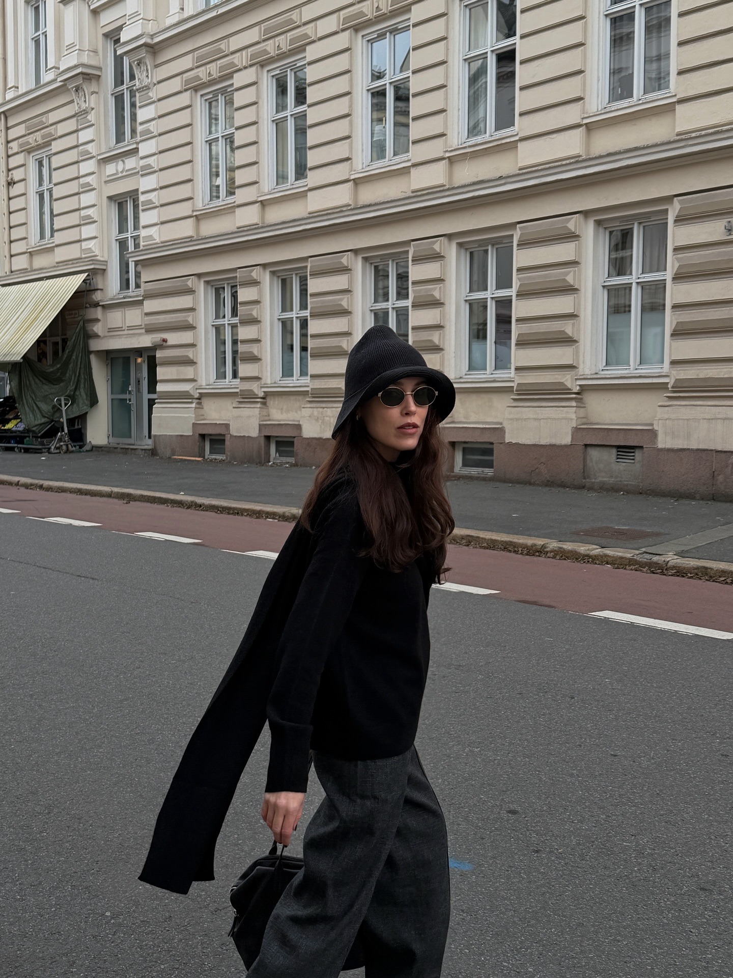Influencer @annabelrosendahl walks down the street wearing a knitted bucket hat with a black jumper and grey trousers.