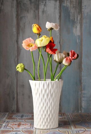 orange, white and yellow poppies in a white vase