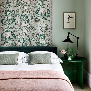 green and pink bedroom with a green rug behind the green headboard and a matching lamp table and lamp and a pink thrown on the bed