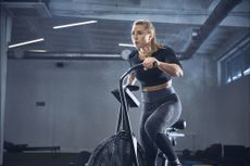 Best air bike: Pictured here, a fit young woman using an air bike in a warehouse-style gym