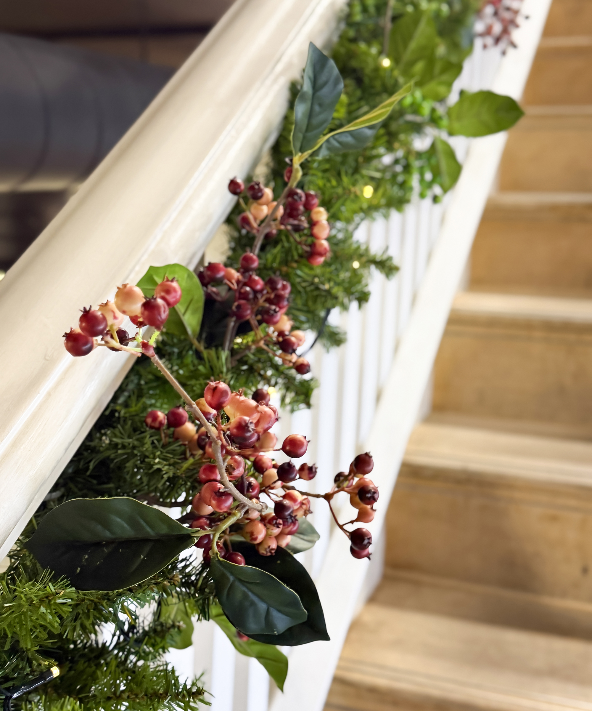 Spruce and variegated holly leaf and red berry garland Christmas decoration on spindles of staircase