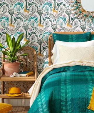A bedroom with a turquoise bed, a shelf with a plant, and colorful peel and stick wallpaper