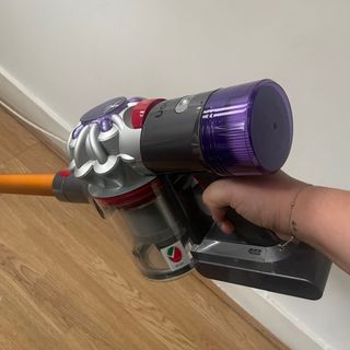 Hand holding the top of the Dyson V8 Absolute