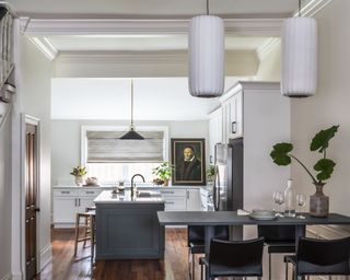 Kitchen diner with table in foreground, island with stools and white cabinets