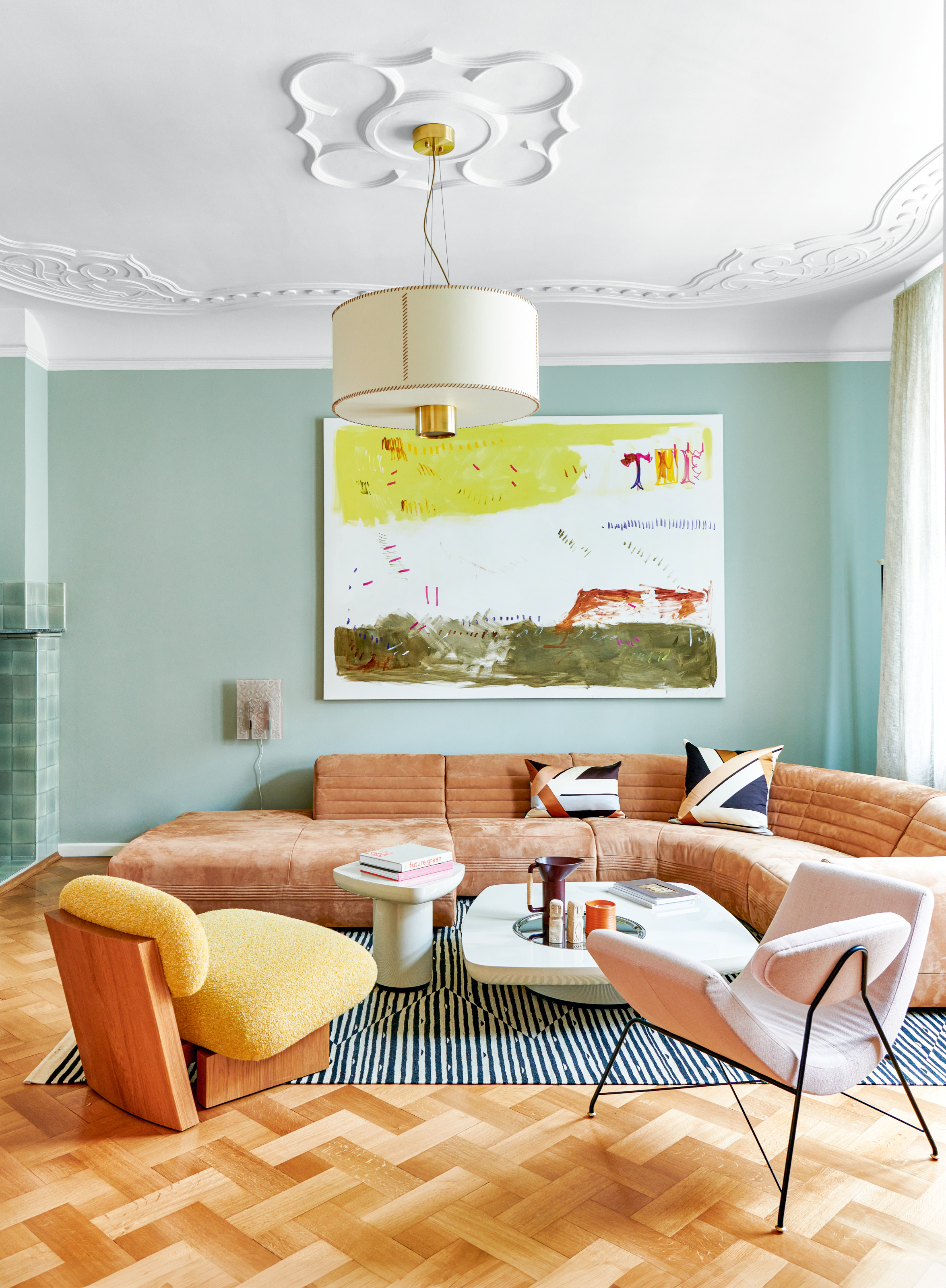 Blue living room with tan curved corner sofa, yellow armchair and parquet flooring
