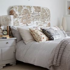 bedroom with white wall and pillows on white bed near lamp 