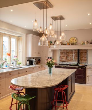 kitchen with large island with curved end, series of fluted glass pendants hung from metal plates above island