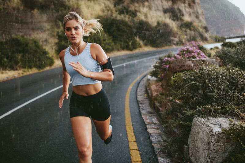 A female runner jogs along a road in the rain