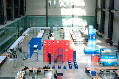 Turbine Hall with plastic boxes and people as the workshop is set-up
