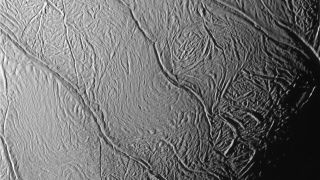 a close up view of an icy moon of saturn showing deep fissures along its surface