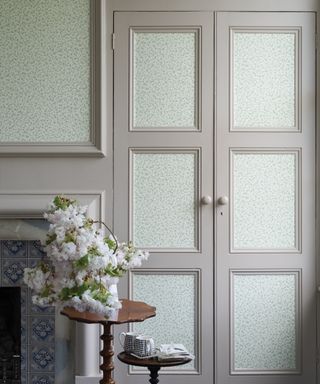 An example of how to hang wallpaper on gray cupboard doors, beside a traditional dove gray fireplace.