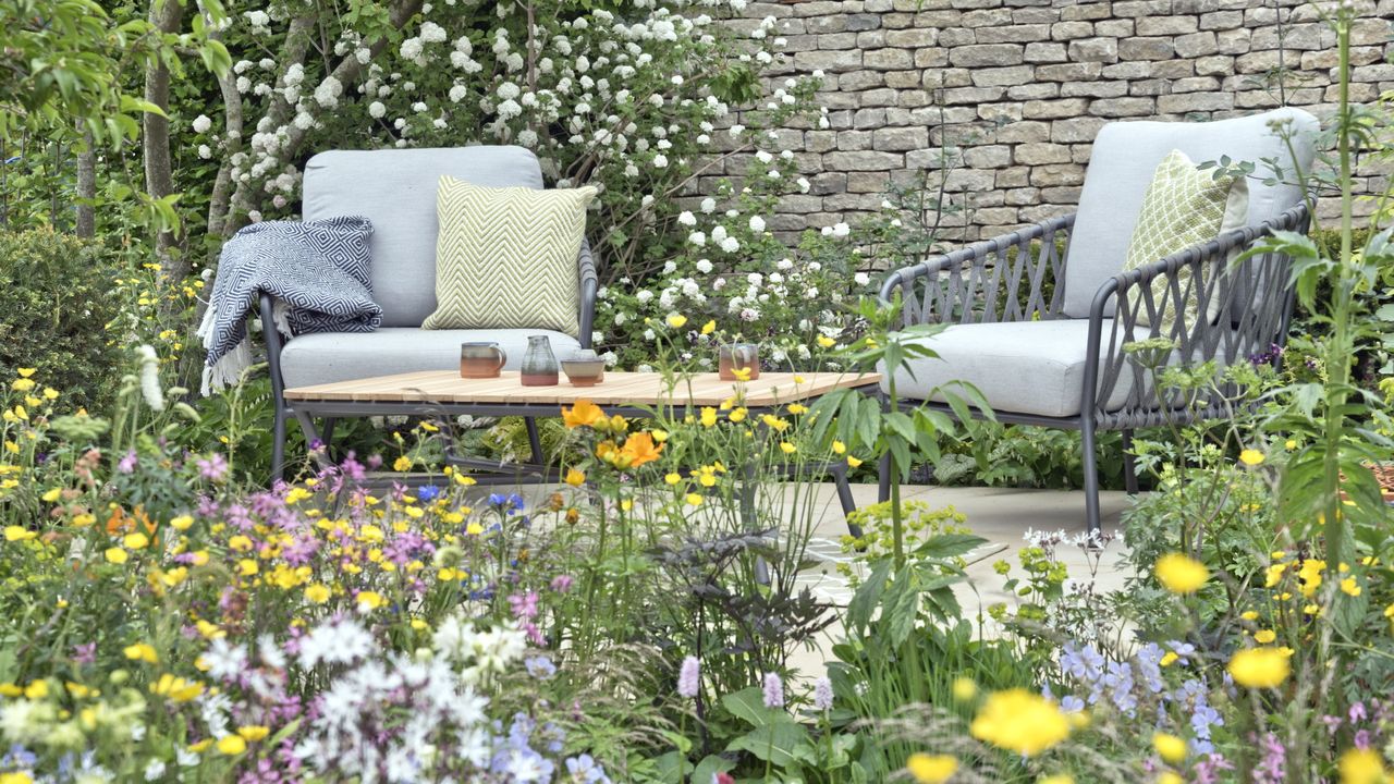 Stylish table and chairs set behind meadow-like planting