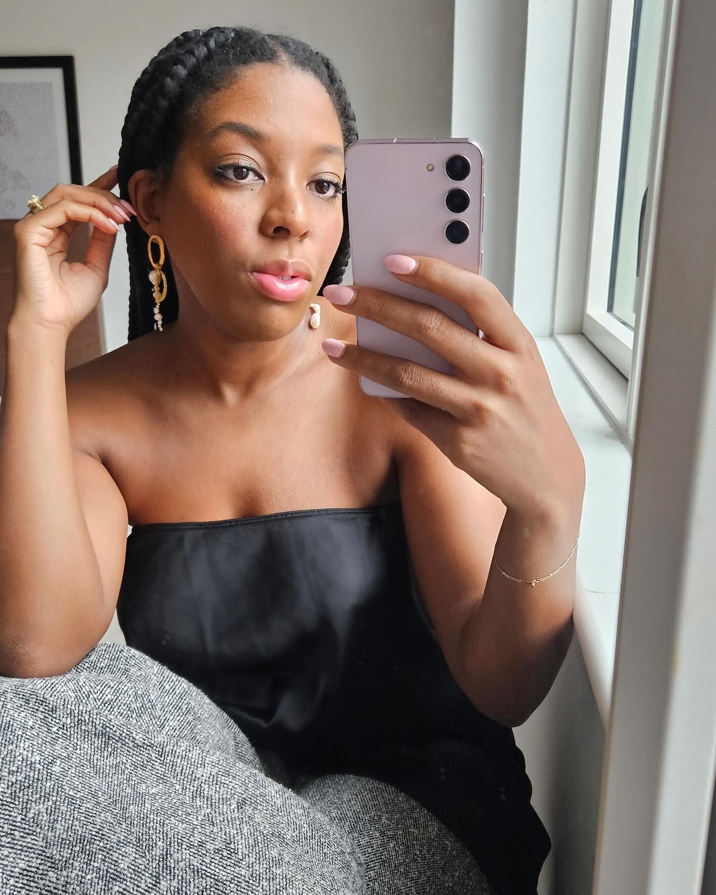 Remy wears a black strapless top and grey trousers