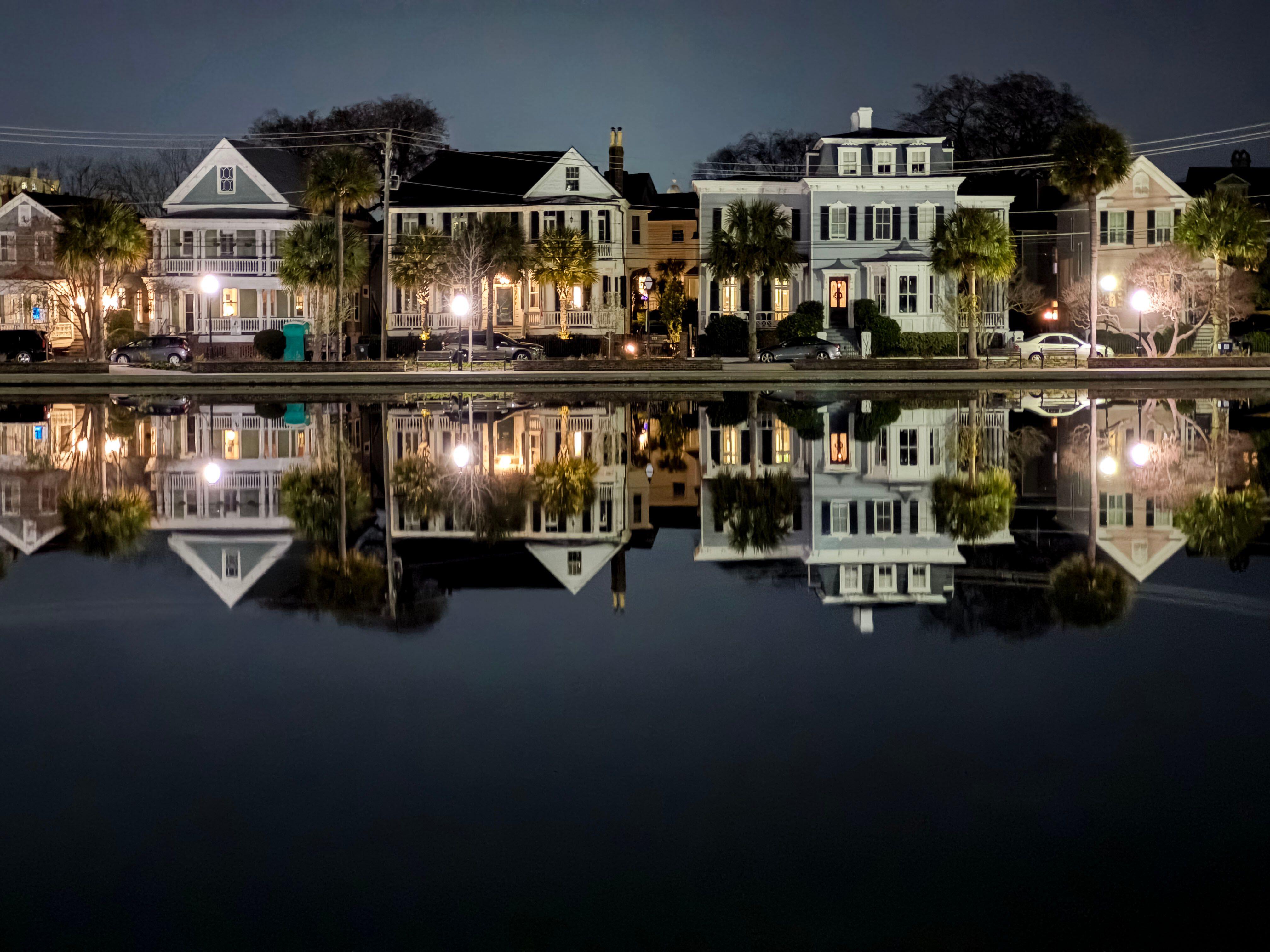 Serene nighttime view of historic houses reflected in the calm waters of Colonial Lake in Charleston, South Carolina
