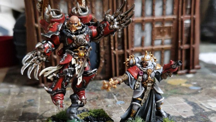 A Chaos Space Marine Lord and Sister of Battle miniature beside on another on a painting mat, in front of a ruined building