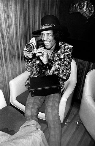 Photo of Jimi HENDRIX; posed at press conference on top of Pan Am building, holding cine-camera
