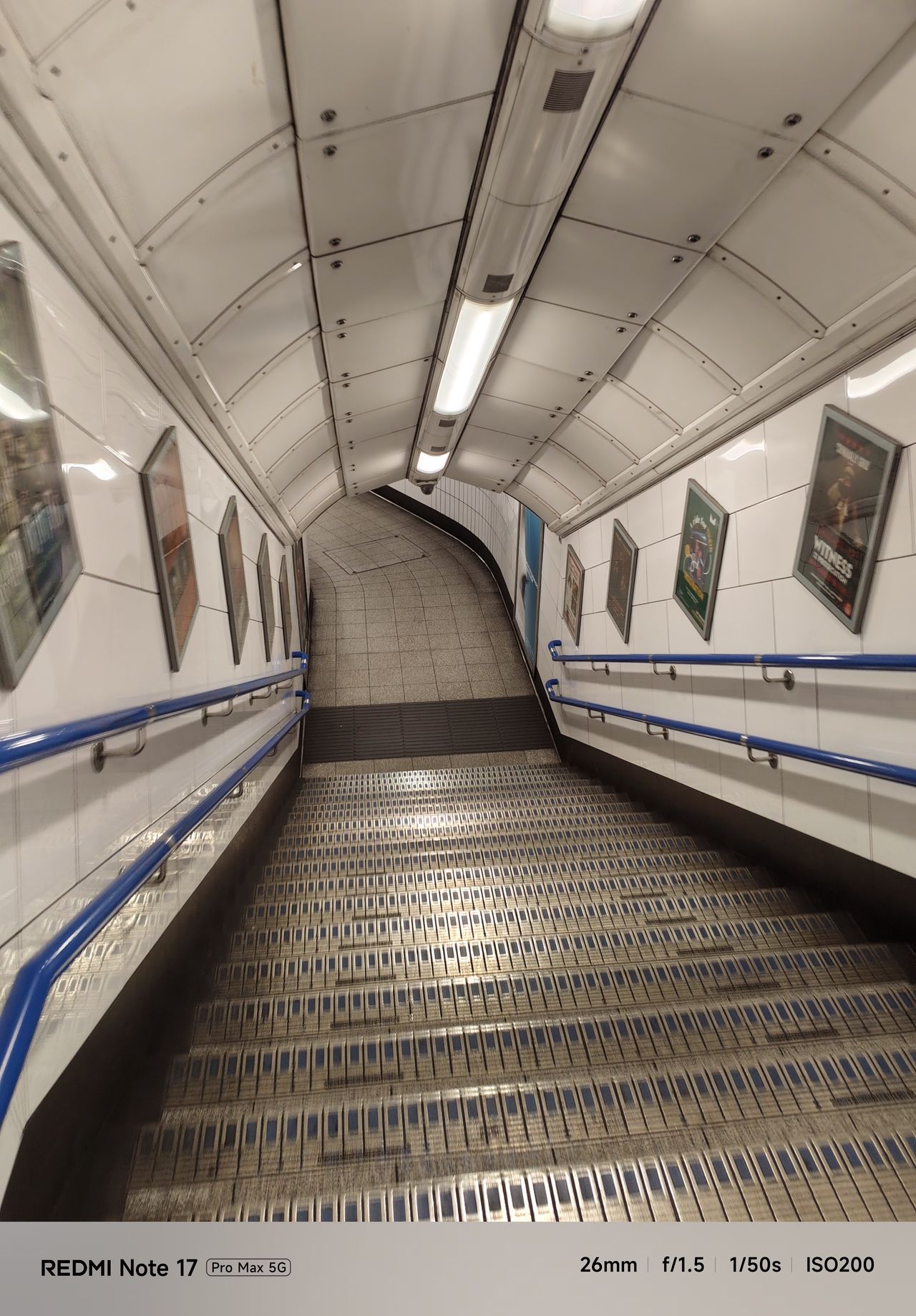 Curving staircase and tiled walls inside a London Underground station.