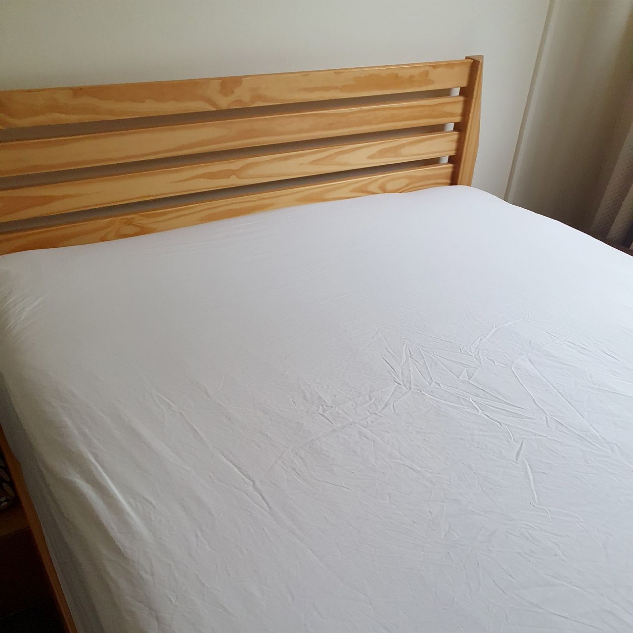 Black elasticated sheet straps being fitted to a white fitted sheet