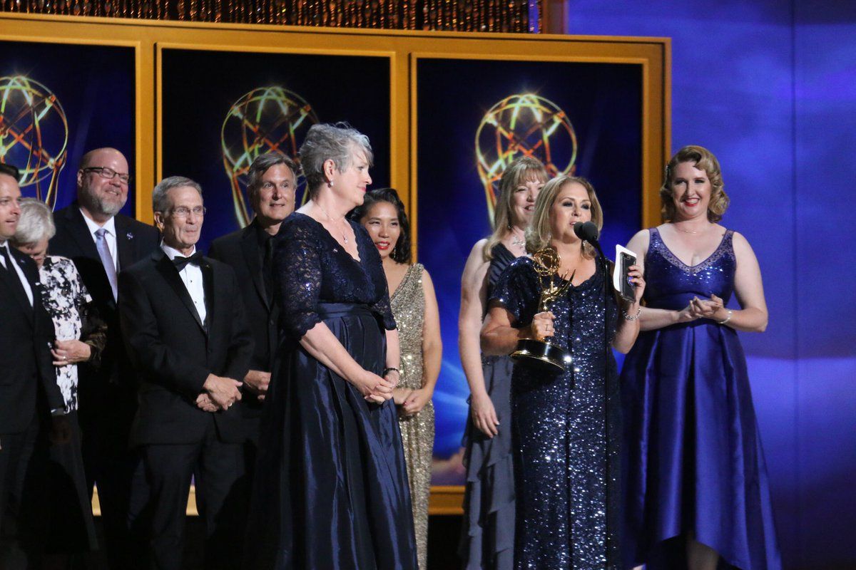 People pose as they receive an award in long formal sparkly dresses and suits