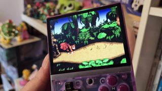 Photo of writer Rosalie Newcombe holding up the Miyoo Mini Plus handheld while it's running Donkey Kong Country on the SNES.