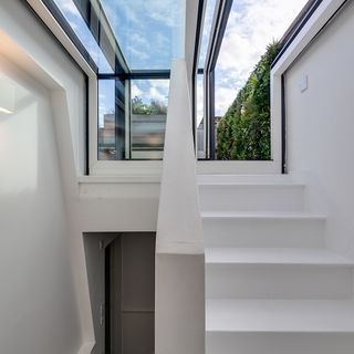 stairway with white wall and glass roof window