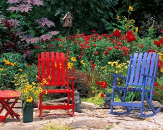Whimsical summer garden in red with red furniture and flowers blooming, Missouri USA