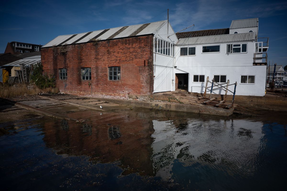 Dockside industrial building, reflected in still clear water on a sunny day