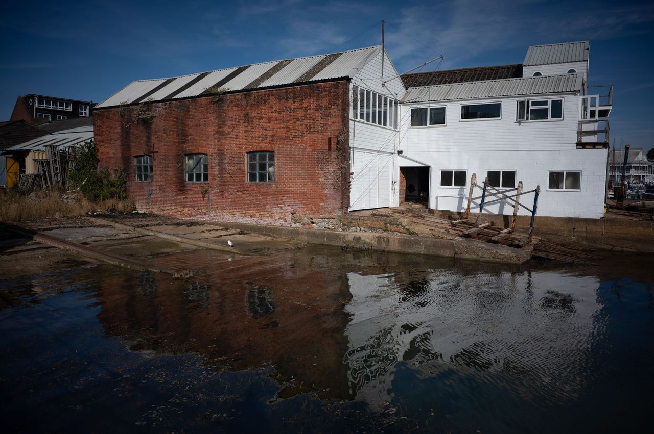 Dockside industrial building, reflected in still clear water on a sunny day