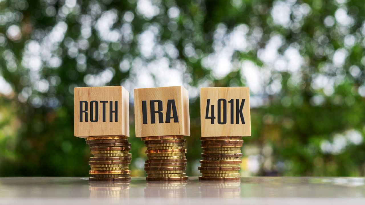 The words, letters and numerals Roth, IRA and 401(k) on blocks sitting atop stacks of coins.