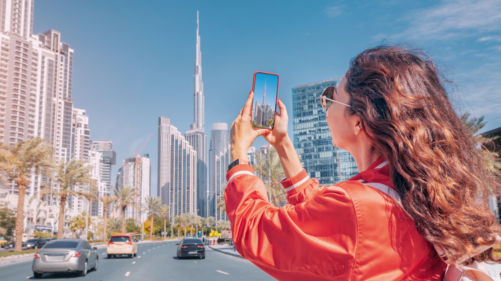 Woman taking a photo on a smart phone in front of the Burj Khalifa 