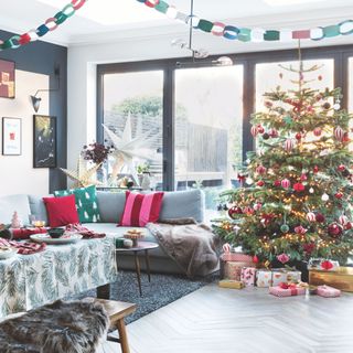 Decorated Christmas tree beneath colourful paper chains in living room and dining room area