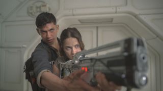 Archie Renaux instructs Cailee Spaeny on how to use a pulse rifle in Alien: Romulus.