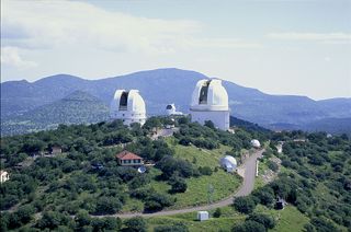 The two large domes in the foreground house the 2.1-meter (82-inch) Otto Struve Telescope (left) and the 2.7-meter (107-inch) Harlan J. Smith Telescope (right). Between these two, the Hobby-Eberly Telescope (HET) can be seen, atop neighboring Mt. Fowlkes