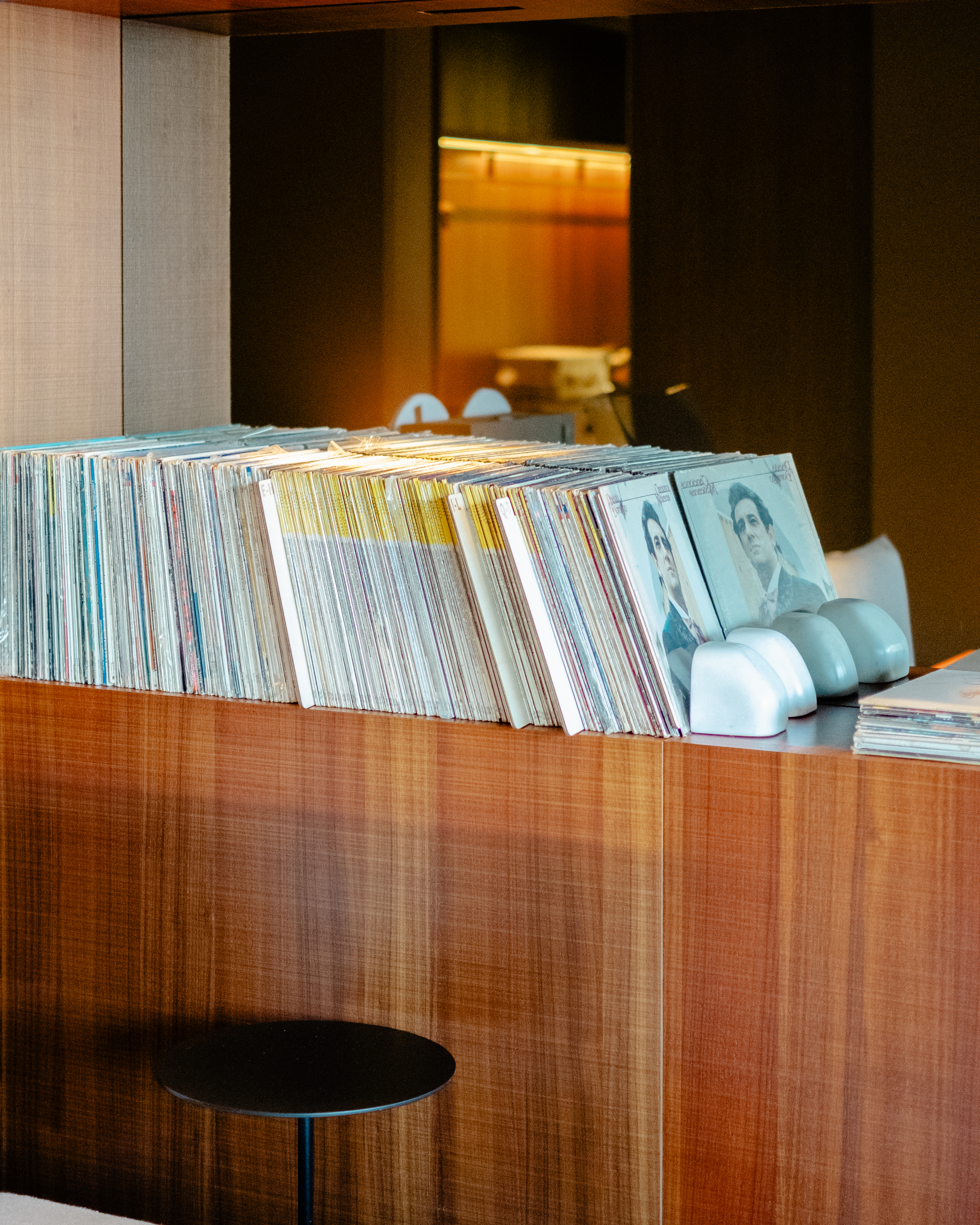 A high-fidelity suite fitted with retro-inspired amplifiers, speakers, a turntable, and a sprawling record collection features a mid-century-cool vibe through wood-clad surfaces and sculptural designs.