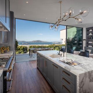 A white a grey kitchen with marble counters and bi-fold doors with sea views in a house which once belonged to Meg Ryan