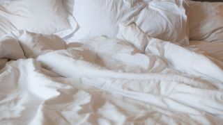 A messy bed with comforter and pillows - stock photo