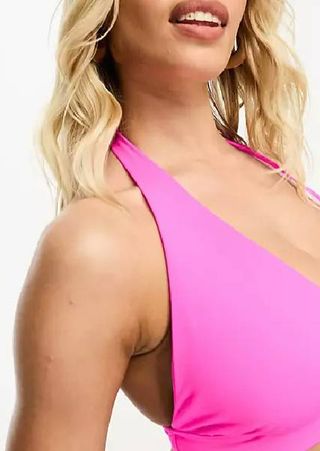 A close up of a model wearing a bright pink bikini top from ASOS.