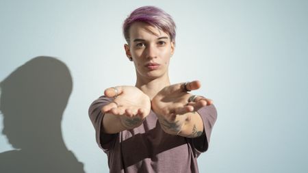 A young adult holds out their hands as if for cash, looking a bit entitled.
