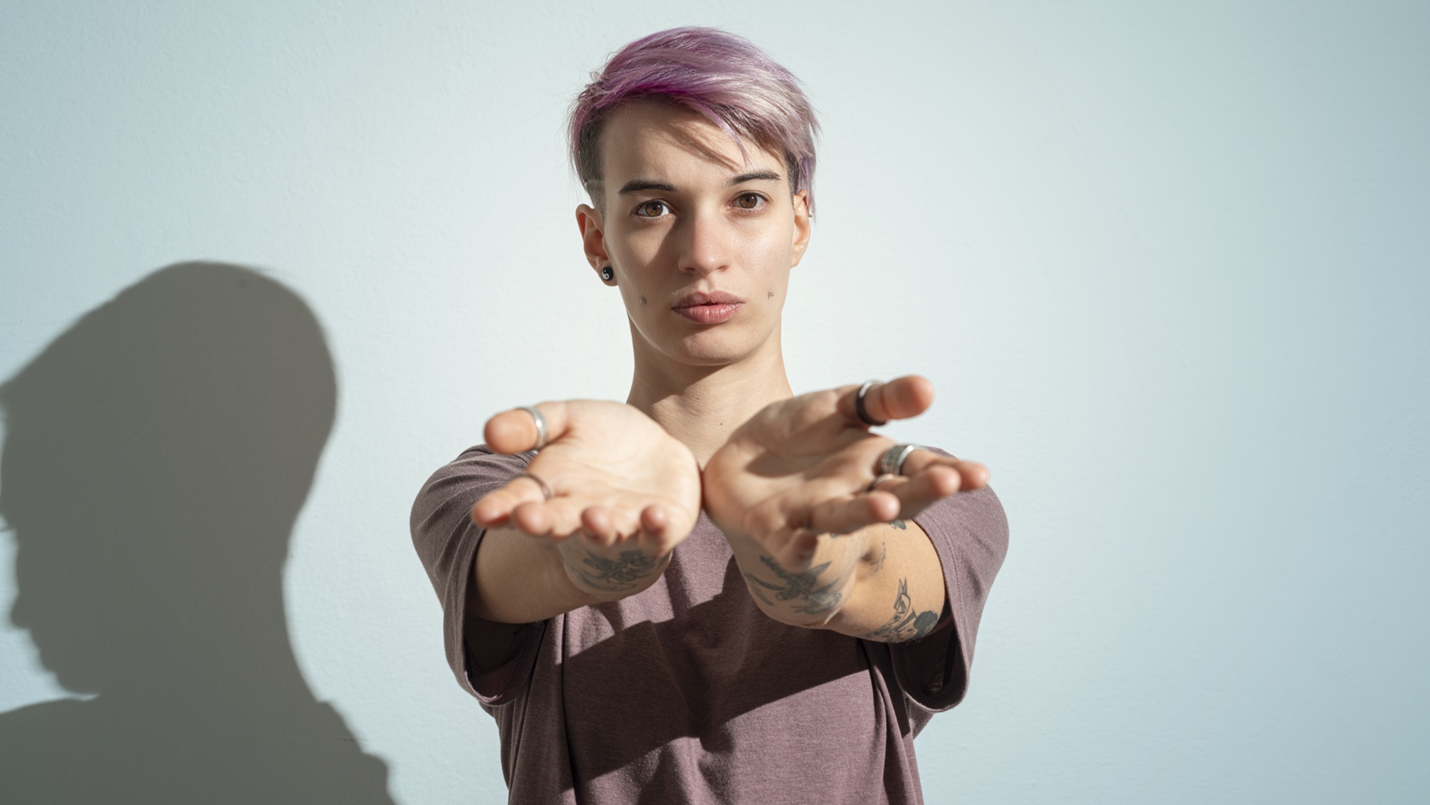 A young adult holds out their hands as if for cash, looking a bit entitled.