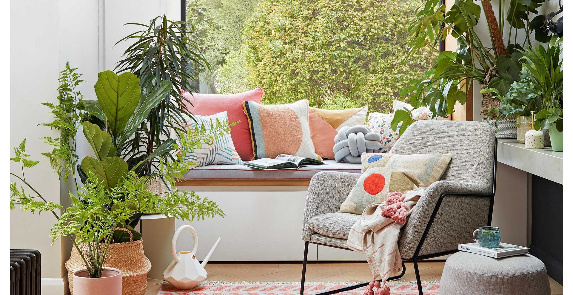 contemporary living room with large box window with window seat surrounded with lots of plant to show how to transform a living room on a budget