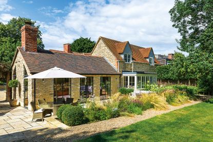 Cottage with modern extension and back garden with mature planting and parasol 