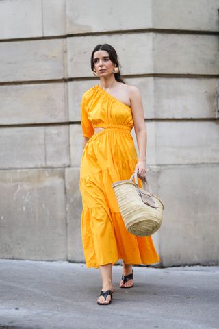 Woman wearing orange dress and carrying beach bag