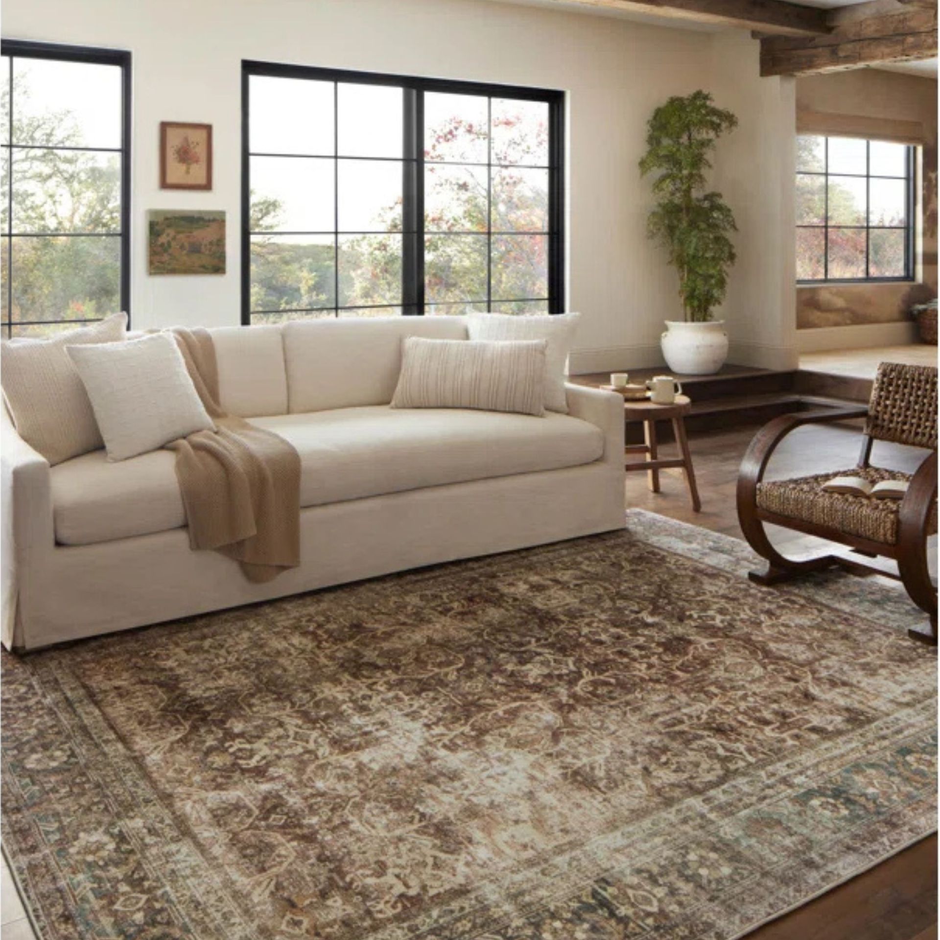 Magnolia Home By Joanna Gaines X Loloi rug with a white sofa and rattan chair against white walls.